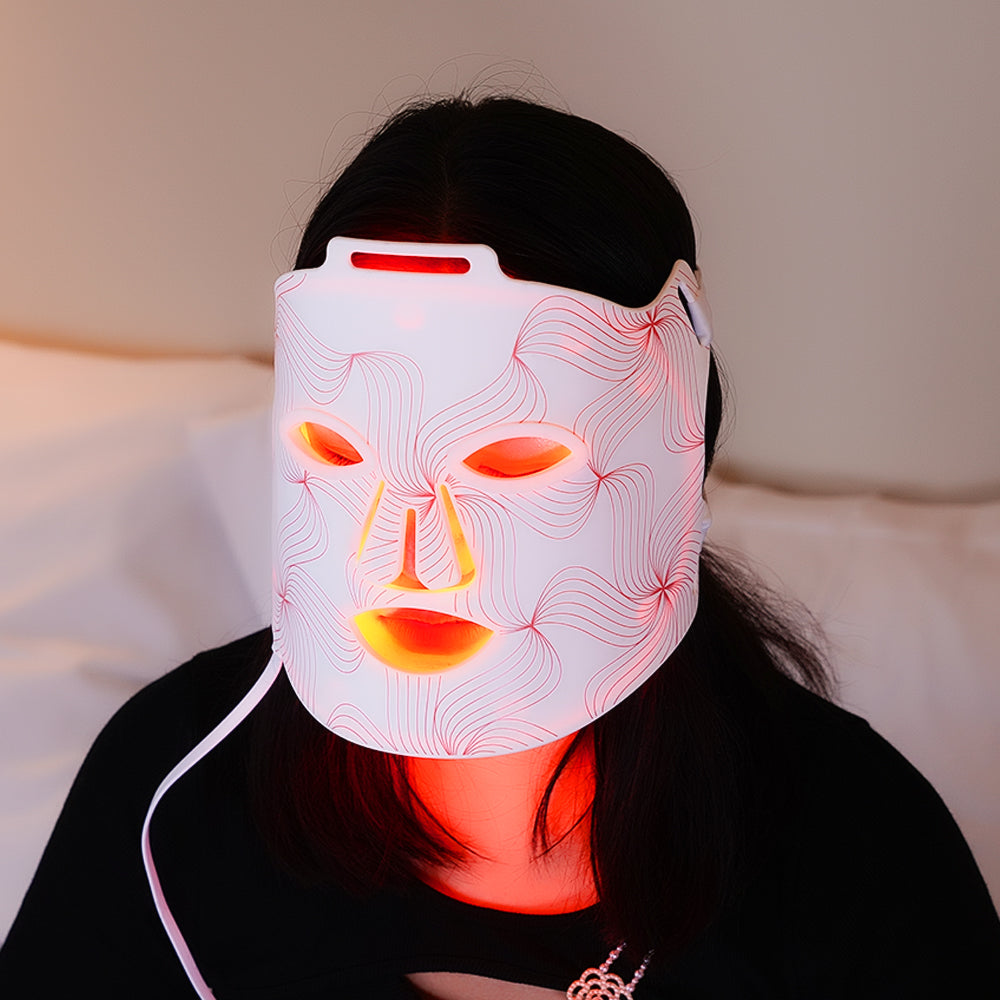 Modèle utilisant le masque LED visage et cou anti-âge, activé en mode thérapie lumière rouge pour des soins complets.